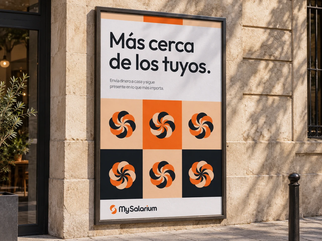 The Más cerca de los tuyos campaign displayed as a framed street poster on a sunlit stone facade